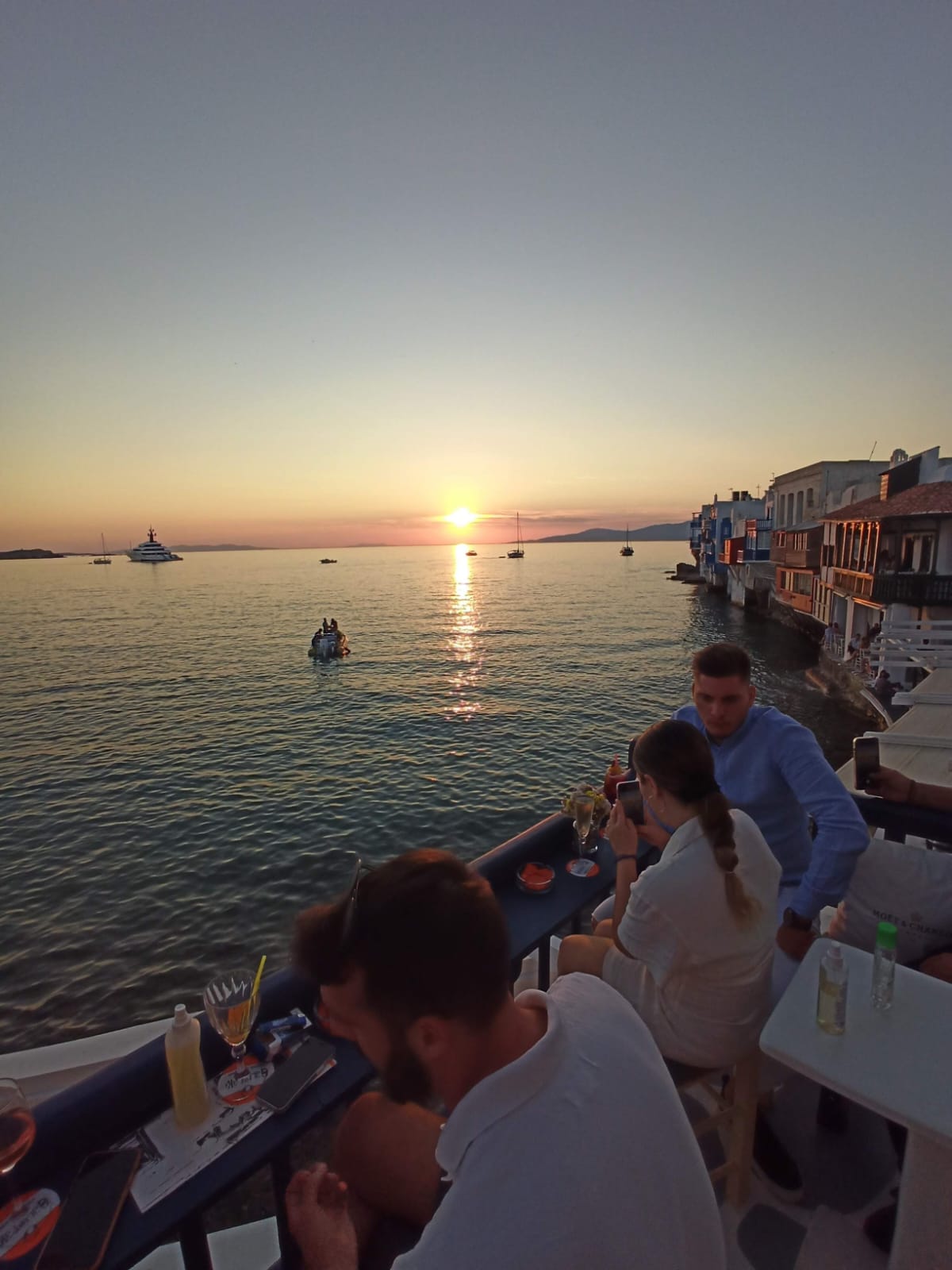 People with cocktails on a balcony, at sunset